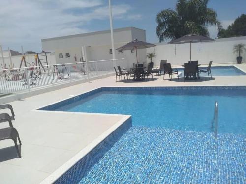 ピサーハスにあるResidencial Angelus Condomínio Clube na Praia de Piçarrasのスイミングプール(椅子、テーブル、パラソル付)