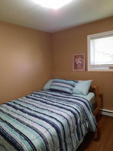 a bedroom with a bed with a striped comforter at Lovely 2 Bedroom apartment close to Avalon Mall in St. John's