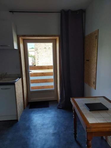 une cuisine avec une porte, une table et une fenêtre dans l'établissement Petite maison de campagne, à Castillon-de-Castets
