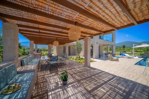 a patio with a wooden pergola and a swimming pool at Claire villa in Sami