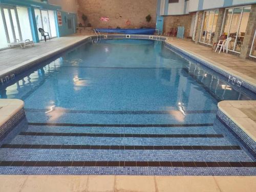 a swimming pool with blue water in a building at Wood View - Penstowe Park in Kilkhampton