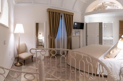 a white bedroom with a bed and a chair at INSULA LUBRENSIS flat in Massa Lubrense