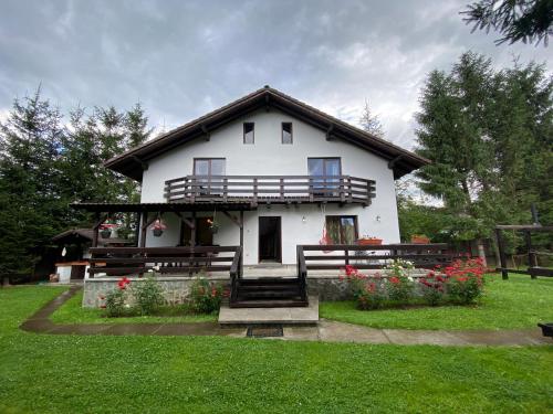 a white house with a balcony and flowers in the yard at Vila Alunis 2 in Bran
