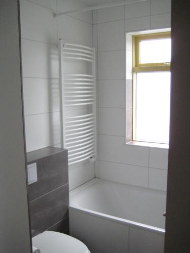 a bathroom with a tub and a toilet and a window at Central Reykjavík Apartment in Reykjavík