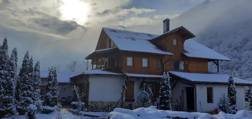 a house covered in snow with the sun behind it at Gasthaus Maria in Borlova