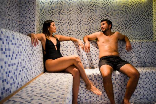 a man and a woman sitting on a bed at Hotel Cálido Termal in Termas de Río Hondo