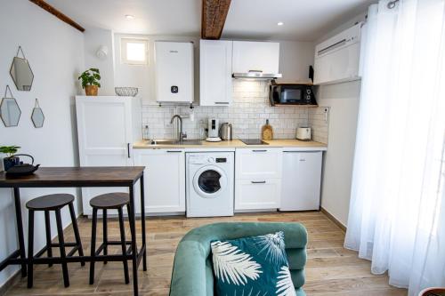 eine Küche mit weißen Schränken sowie einem Tisch und Stühlen in der Unterkunft Élégant Studio Climatisé 'Alma 2' - Cœur de Beziers - Wifi Fibre - Netflix in Béziers