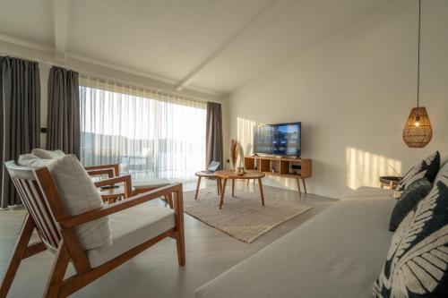 uma sala de estar branca com uma televisão e uma mesa em Gizz Suites em Fethiye