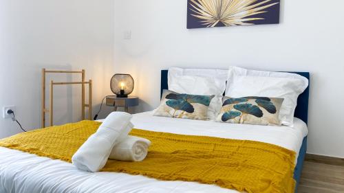 ein Bett mit einer gelben Decke und Kissen darauf in der Unterkunft Élégant Studio Climatisé 'Alma 2' - Cœur de Beziers - Wifi Fibre - Netflix in Béziers