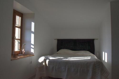 a bed in a white room with a window at Ancienne ferme tranquille en Haute Ardèche in Étables