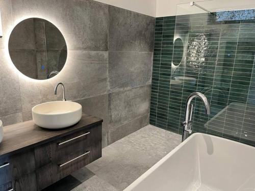 une salle de bain avec un lavabo, une baignoire et un miroir dans l'établissement Villa de charme, à Châteauneuf-de-Gadagne