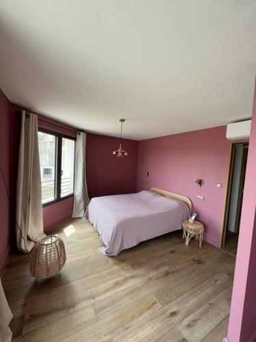 - une chambre avec des murs roses et un lit revêtu de parquet dans l'établissement Villa de charme, à Châteauneuf-de-Gadagne