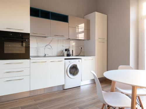 a white kitchen with a washing machine and a table at Maestrale Apartment in Cagliari