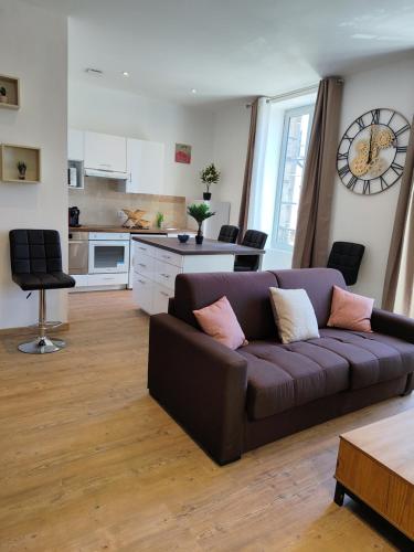 a living room with a brown couch and a kitchen at Blum in Brive-la-Gaillarde