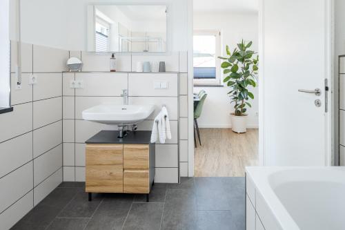 Baño blanco con lavabo y espejo en FENJOY: Ferienapartment mit Balkon / Zentral / BBQ, en Bernau am Chiemsee