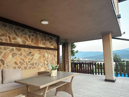 un patio con una mesa de madera y una pared de piedra en Villa Monte, en Velingrad