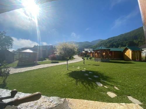 a sun shining on a field of grass with houses at Ethno House Bektesevic in Gusinje