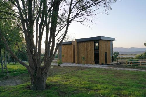 un pequeño edificio de madera en un campo con un árbol en Salinas Nest - Ulcinj Stoj Ada Bojana en Ulcinj
