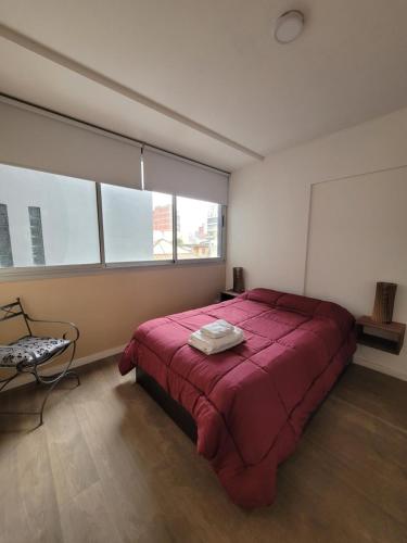 a bedroom with a red bed in a room with windows at Hermoso departamento en Flores! in Buenos Aires