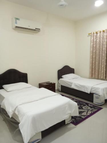 two beds in a room with white walls at Argaan Apartment in Salalah