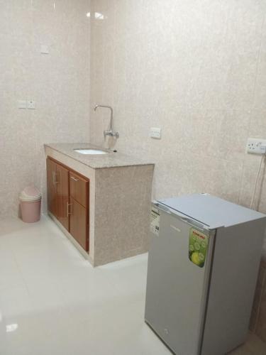 a small kitchen with a sink and a refrigerator at Argaan Apartment in Salalah