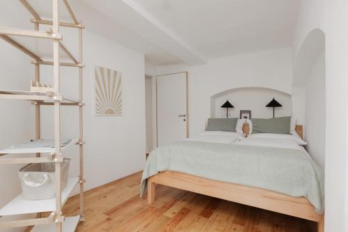 a white bedroom with a bed and a wooden floor at Das Grüne Haus - Boutique Apartments ecofriendly in Innsbruck