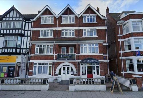 a large brick building with a sign on it at Coasters Holiday Apartments in Skegness