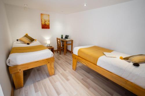 a bedroom with two beds and a table with a chair at Hotel Don Raul in San Pedro de Atacama