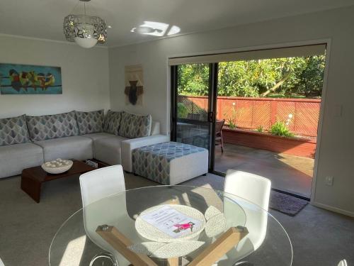 a living room with a couch and a glass table at Baybell Lodge in Tauranga