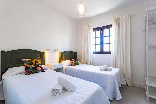 a room with two beds with white sheets and a window at Villa Tara in Tías