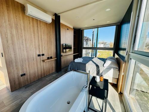 a bathroom with a tub and a bed and a bedroom at Cubos de Chacras AZUL in Mendoza
