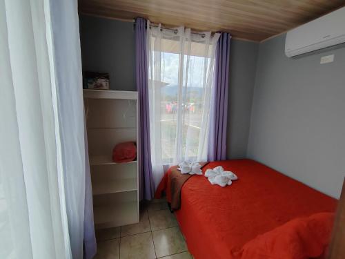 Un pequeño dormitorio con una cama roja y una ventana en Apartamento de una habitación, en San Isidro