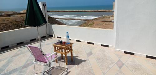a chair and an umbrella on a balcony with the ocean at REPOS SURF HOUSE 2 in Sidi Ifni
