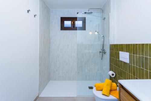 a bathroom with a shower and a toilet with yellow towels at Villa Tara in Tías