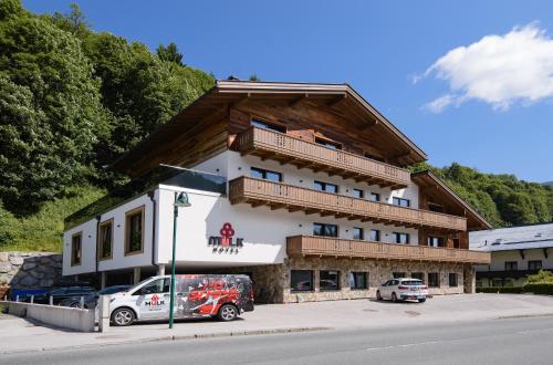 een groot gebouw met auto's geparkeerd voor het bij Mulk Hotel - Joker Card included in Summer in Saalbach Hinterglemm