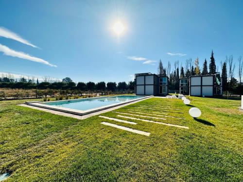 a swimming pool in the middle of a grass field at Cubos de Chacras AZUL in Mendoza