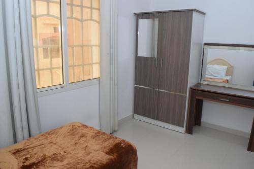 a bedroom with a wooden cabinet and a mirror at RED-7 - Alwadi Salalah in Salalah