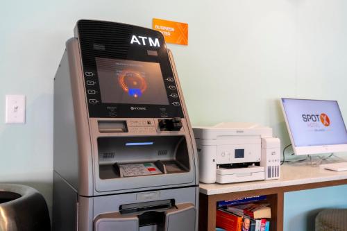 an atm machine sitting next to a desk with a computer at SPOT X Hotel Orlando Intl Dr by The Red Collection in Orlando