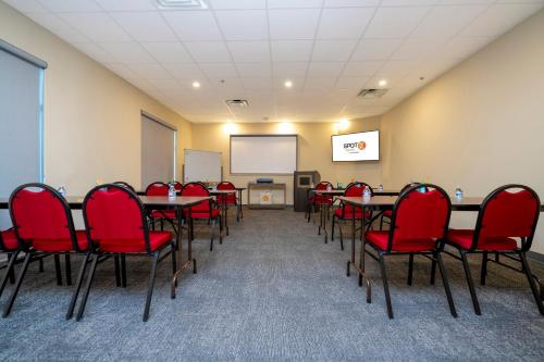a conference room with tables and red chairs and a screen at SPOT X Hotel Orlando Intl Dr by The Red Collection in Orlando