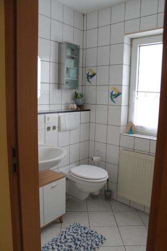 a white bathroom with a toilet and a sink at Gemütliches Apartment, nahe Wetzlar in Wetzlar