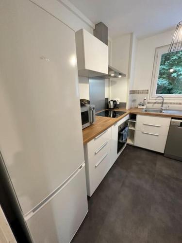 une cuisine avec des armoires blanches et un évier dans l'établissement Appartement 4 pers. avec parking gratuit sur place Petit Couronne, à Le Petit-Couronne