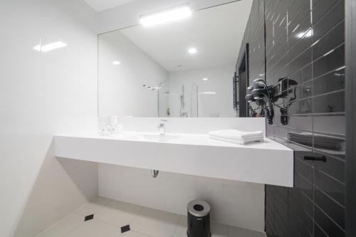 W łazience znajduje się biała umywalka i lustro. w obiekcie VacationClub - Czarna Perła Apartament 303 w Stroniu Śląskim