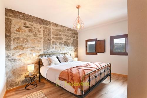um quarto com uma cama e uma parede de pedra em Casa do Alfaiate by TonsdeVerde em Vila Verde