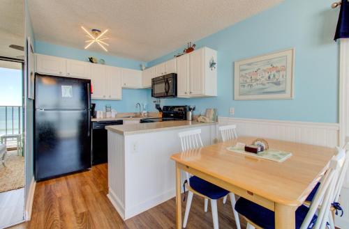 cocina con mesa de madera y nevera negra en 0601 Seaclusion by Atlantic Towers, en Carolina Beach