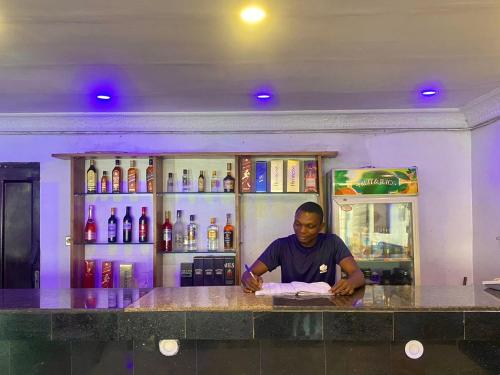 a man sitting at a counter in a bar at Presken Hotel @Villa in Ikeja