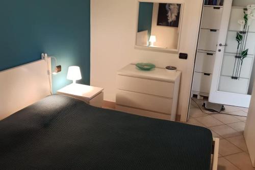 a bedroom with a bed with a lamp and a dresser at Villa con porticato sul prato in Isola Albarella