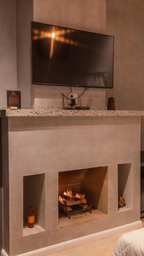 a fireplace with a television on top of it at Hotel Chalés Capitanias in Águas de Lindóia
