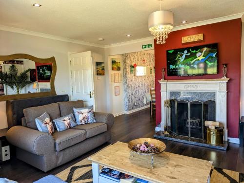 a living room with a couch and a fireplace at FINN VILLAGE "Mountain View Cottage" Private Garden, 9-seater Hot Tub, Firepit & Pizza Stove in Drymen