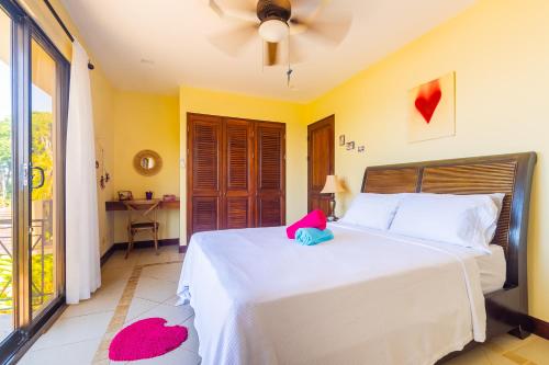 a bedroom with a white bed with a pink stuffed animal on it at Villa Amor del Mar with Breathtaking View of Ocean & Jungle in Dominical