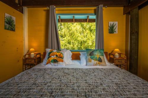 a bedroom with a large bed with a window at Arevareva Pole House Papeete in Papeete
